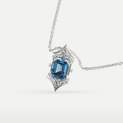 Close-up of a silver pendant necklace featuring an emerald-cut gemstone surrounded by intricate detailing and sparkling accent stones.